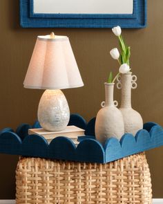 two vases and a lamp on a wicker table in front of a painting