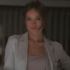 a woman wearing a white jacket and necklace