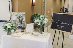 the table is set up with pictures and flowers for guests to sign in front of them