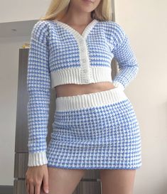 a blonde woman in a blue and white sweater and skirt posing with her hands on her hips