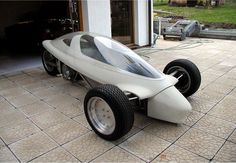 an electric car is parked in front of a garage with its door open and wheels down