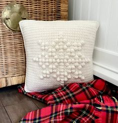 a white pillow sitting on top of a wooden floor next to a basket and blanket