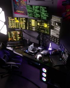 a computer desk with multiple monitors and laptops on it, all lit up at night