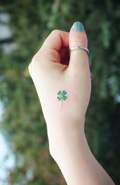 a person's hand with a small green clover tattoo on it, and the other arm