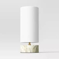 a white table lamp with a marble base and gold trim on the top, against a plain background