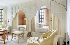 a living room filled with furniture next to a window covered in white drapes and curtains