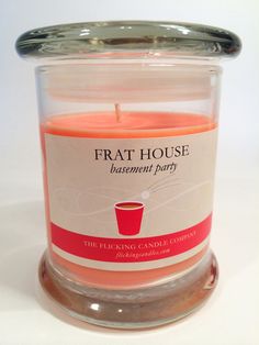 a lit candle in a glass container with a label on the lid that says frat house