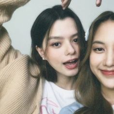 two young women posing for the camera with their hands in the air and one holding her hair up