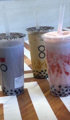 three bubble teas are lined up on a table