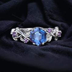 an elegant ring with blue topaz and purple stones on a black cloth, close - up