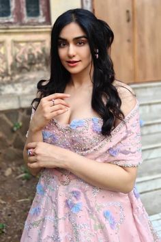 a woman in a pink dress posing for the camera with her hand on her chest