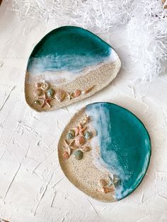 two ceramic plates with shells and sand on them