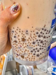 a person holding a drink in their hand with stars on the cup and nail polish