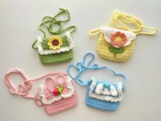 four crocheted purses sitting on top of a white table next to each other