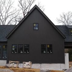 a black house with three windows and some rocks