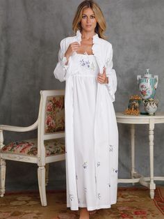 Designed to set hearts aflutter, this poetic gown of fine White cotton batiste is delicately hand embroidered with a sprig of lavender Wisteria on the bodice and falling blossoms on the skirt. Styled for flattering fit, it has a shirred elastic empire waist, drawstring top and adjustable spaghetti straps. A matching tie-front robe is beautifully ruffled around the becoming V-neck and long sleeves. Imported. Sleeping Gown Nightgowns, Linen Nightwear, Lavender Wisteria, Elegant Nightgown, Linen Nightgown, Moda Kimono, Pretty Robes, Beautiful Nightgown, Linen Sleepwear