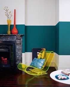 a living room with green and white stripes painted on the walls, yellow chair in front of fireplace