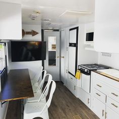 the interior of a mobile home with white cabinets and wood flooring, including a dining table