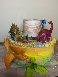 there is a cake decorated with dinosaurs on the top and a candle in the middle