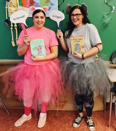 two girls dressed in costumes holding up books