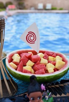 a bowl of watermelon and pineapple next to a pool