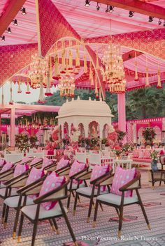 pink and white wedding setup with chandeliers, chairs, and tables in the background