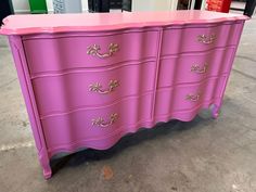 a pink dresser with gold handles in a room