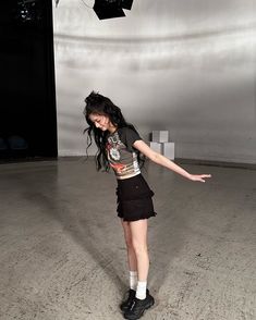 a young woman standing on top of a cement floor in front of a black umbrella