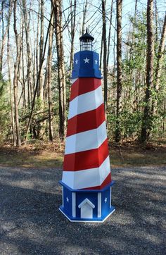 a red, white and blue light house in the woods