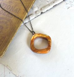 Love this resin carnelian orange hoop because of its simplicity and also it reminds me of Bakelite.  I have soldered this acrylic ring/hoop using the copper foil stained glass technique, then finished the solder with an antiqued patina.  The pendant measures 1.5" wide, and just over .75" thick and hangs from a delicate 18" antiqued brass chain. The pendant is lightweight and interesting.    **Lucite, a form of acrylic resin, appeared in many colors and styles of jewelry during the 1940s and 1950s. It comes in virtually every hue, in both transparent and solid forms. Similar to Bakelite, another popular mid-century resin material, it's become collectible in recent years. Lucite is still used today in the production of some jewelry. View more recycled Lucite and resin necklaces here -  https Brown Resin Jewelry Gift, Brown Resin Jewelry For Gifts, Orange Resin Jewelry For Gift, Orange Vintage Copper Jewelry, Handmade Tortoiseshell Jewelry Gift, Vintage Amber Resin Jewelry, Unique Orange Resin Jewelry, Unique Orange Round Pendant Jewelry, Vintage Orange Metal Necklace