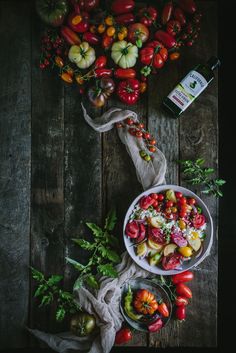 two bowls filled with different types of vegetables next to a bottle of wine on a wooden table