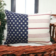 an american flag pillow sitting on top of a wicker basket next to a potted plant