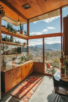 a kitchen with wooden cabinets and windows overlooking the mountains in front of it is shown