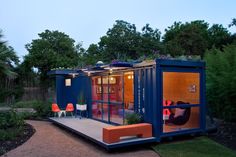 a blue shipping container with its doors open and some chairs on the deck in front of it