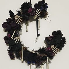 a wreath made out of fake flowers and skeleton bones hanging on a wall in front of a white wall