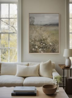 a living room filled with furniture and a painting hanging on the wall over a white couch