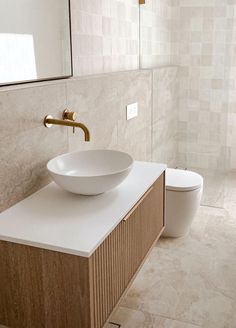 a white bowl sink sitting on top of a counter next to a toilet in a bathroom