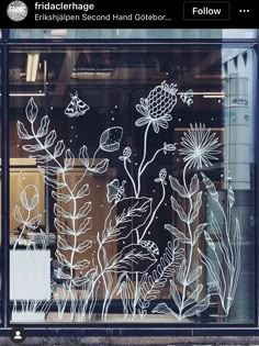 the window is decorated with white flowers and plants on it's glass, which has been drawn onto by hand