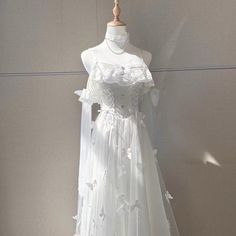 a white wedding dress is displayed on a mannequin headdress with flowers