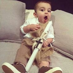 a baby is sitting on a couch with an umbrella in it's lap and yawning