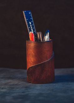 a leather pen holder with pens and scissors in it