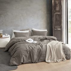 a large bed sitting next to a window in a room with grey walls and wooden floors