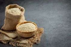 a sack of rice next to a wooden spoon on a cloth with a bag in the background