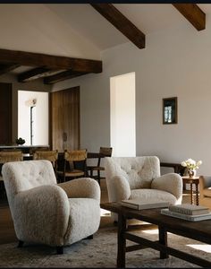 a living room filled with furniture next to a wooden table and ceiling mounted light fixture