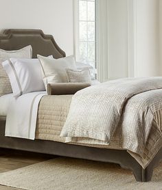 a bed with white and beige comforters in a bedroom