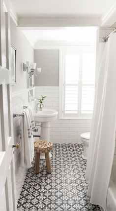 a white bathroom with black and white tile flooring