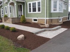 a green house with landscaping in the front yard