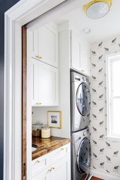 a washer and dryer in a small room next to a window with horse wallpaper