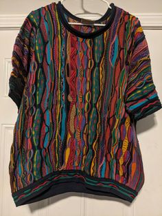 a multicolored sweater hanging on a white door with a hanger in front of it