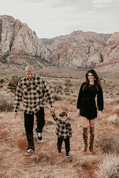 a man and woman walking in the desert with a child on their lap while holding hands